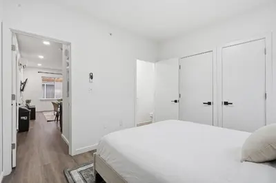 a white bedroom with a bed and a hallway at Fully equipped apartment in great location in Philadelphia
