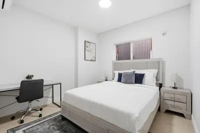 a white bedroom with a bed and a desk at Sleek apartment with modern amenities in Philadelphia