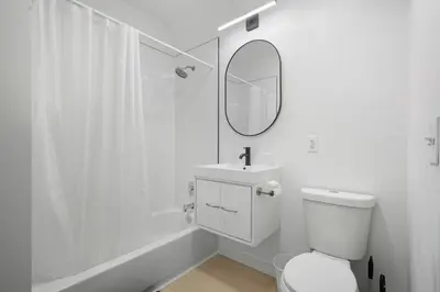 a white bathroom with a toilet and a mirror at Sleek apartment with modern amenities in Philadelphia