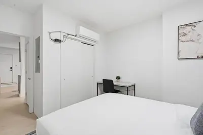 a white bedroom with a bed and a desk at Sleek apartment with modern amenities in Philadelphia