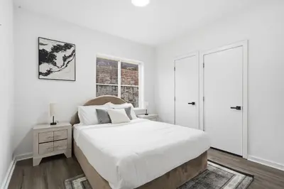 a white bedroom with a bed and a window at Sleek city apartment with modern finishes in Philadelphia