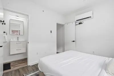 a white bedroom with a bed and a sink at Sleek city apartment with modern finishes in Philadelphia