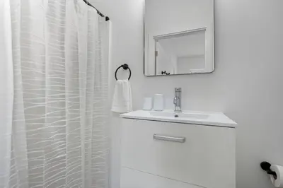 a white bathroom with a sink and a mirror at Sleek city apartment with modern finishes in Philadelphia
