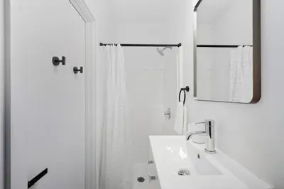 a white bathroom with a sink and a mirror at Sleek city apartment with modern finishes in Philadelphia