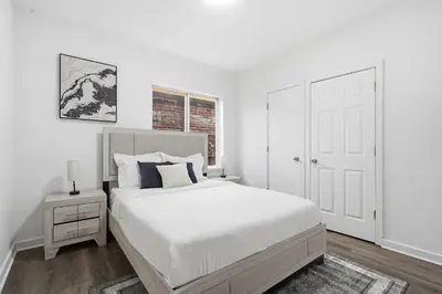 a white bedroom with a large bed and a window at Contemporary apartment with amenities in Philadelphia