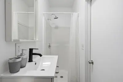 a white bathroom with a sink and a shower at Contemporary apartment with amenities in Philadelphia