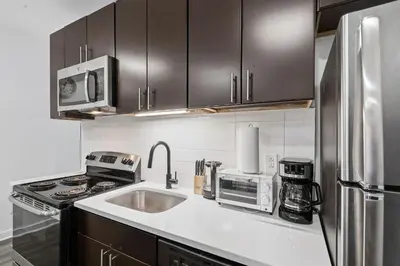 a kitchen with a sink and a stainless steel refrigerator at Contemporary apartment with amenities in Philadelphia