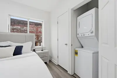 a white bedroom with a bed and a tv at Contemporary apartment with amenities in Philadelphia