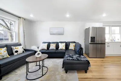 a living room with a black couch and a refrigerator at Family Villa Close to NYC Attractions and Airport in Bayonne