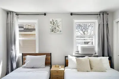 two beds in a room with two windows at Family Villa Close to NYC Attractions and Airport in Bayonne