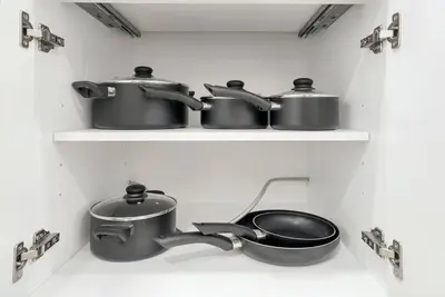 four pots and pans on shelves in a kitchen at Family Villa Close to NYC Attractions and Airport in Bayonne