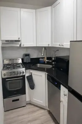 a kitchen with white cabinets and a stove and a sink at Minimalist Midtown West Studio in Central Manhattan in New York
