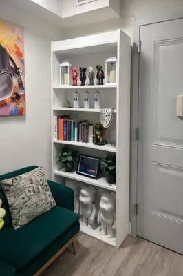 a living room with a green couch and a book shelf at Minimalist Midtown West Studio in Central Manhattan in New York
