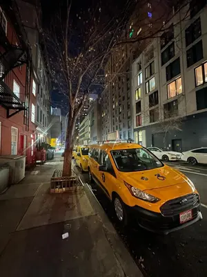 two yellow cars parked on a city street at night at Minimalist Midtown West Studio in Central Manhattan in New York