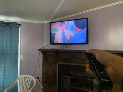 a person holding a remote control in front of a television at Comfortable 3BR, 2BA Perfect for Families! in Mechanicsburg