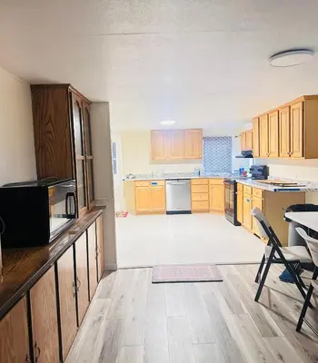 an empty kitchen with wooden cabinets and a table and chairs at Comfortable 3BR, 2BA Perfect for Families! in Mechanicsburg