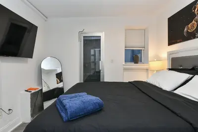 a bedroom with a large black bed and a mirror at Cozy 1BR in Central Manhattan W Private Terrace in New York