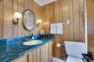 a bathroom with a sink and a toilet and a mirror at Poconos Lakefront Retreat | * Hot Tub * Arcades * in Long Pond