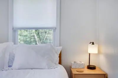 a bedroom with a bed with white pillows and a window at Poconos Lakefront Retreat | * Hot Tub * Arcades * in Long Pond