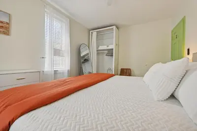 a bedroom with a large white bed with an orange blanket at The Hamilton Elm in Teaneck