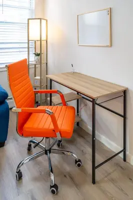 an orange chair sitting in front of a desk at The Hamilton Elm in Teaneck