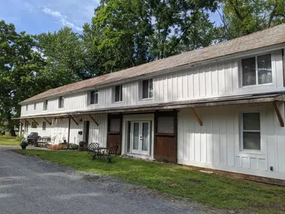 an old white house with a porch and a driveway at Hay Loft in Historic Barn - 4 Minutes to Legoland in Goshen