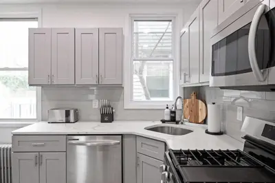 a kitchen with white cabinets and a sink and a stove at The Harper Loft in Hoboken