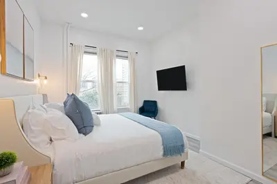 a white bedroom with a bed and a television at The Harper Loft in Hoboken