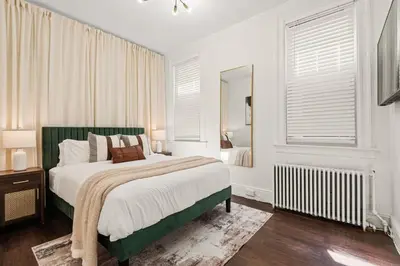 a white bedroom with a large bed and a mirror at The Caleb Loft in Hoboken