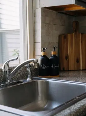 two bottles of soap sitting on a kitchen sink at The Caleb Loft in Hoboken