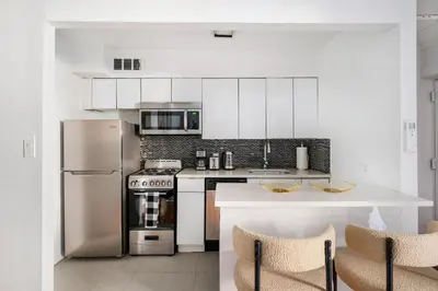 a kitchen with white cabinets and a stainless steel refrigerator at 26-1C Gramercy Large 1BR WD in New York