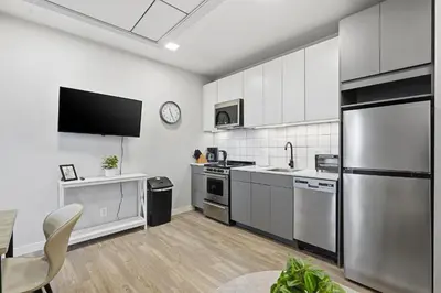 a kitchen with stainless steel appliances and a flat screen tv at Cozy modern studio in prime area in Philadelphia
