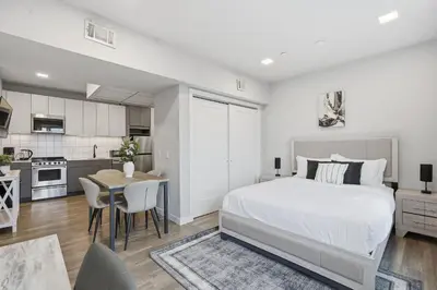 a white bedroom with a bed and a kitchen at Cozy modern studio in prime area in Philadelphia
