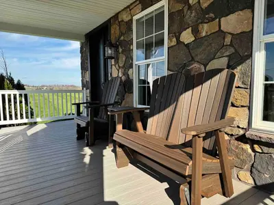 two wooden chairs on a porch with a stone wall at Charming Farmhouse In Quarryville,PA in Quarryville
