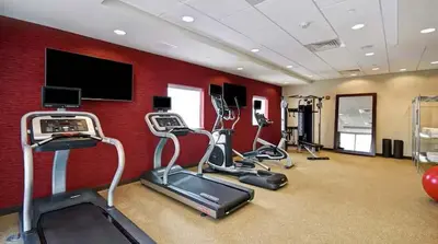 a gym with cardio equipment and a red wall at Home2 Suites by Hilton in Mechanicsburg