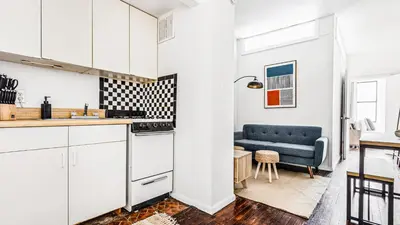 a kitchen with white cabinets and a blue couch at Monthly Furnished 2BD in Hudson Yard, Manhattan, NYC! in New York