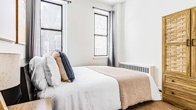 a white bedroom with a bed and two windows at Monthly Furnished 2BD in Hudson Yard, Manhattan, NYC! in New York