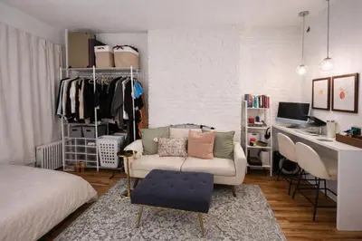 a bedroom with a couch and a desk in a room at Chic West Village Studio on Bleecker Street in New York