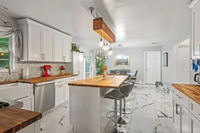 a kitchen with white cabinets and a wooden counter top at Ethereal Haven in West Milford