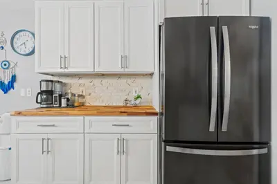 a stainless steel refrigerator in a kitchen with white cabinets at Ethereal Haven in West Milford