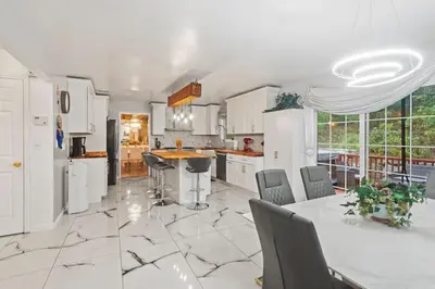 a kitchen with white cabinets and a table and chairs at Ethereal Haven in West Milford