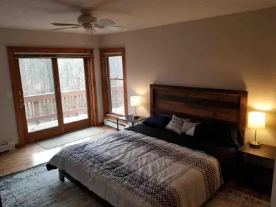 a bedroom with a large bed and two windows at Cozy 4bd 4bath Grand Cabin Retreat in Camelback in Tannersville