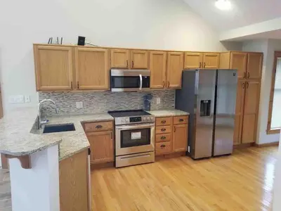 a kitchen with wooden cabinets and stainless steel appliances at Cozy 4bd 4bath Grand Cabin Retreat in Camelback in Tannersville
