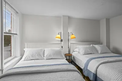 two beds sitting next to a window in a bedroom at Riverfront Gem with Balcony, Patio and City Views in Harrisburg