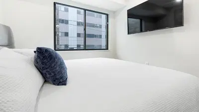 a white bed with a blue pillow and a window at Landing Modern 2BD Gym in Philadelphia
