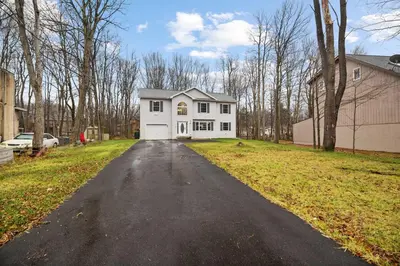 a white house on a street with a driveway at Spacious Vacation Home Tobyhanna Gym BBQ Boat in Pocono Country Place