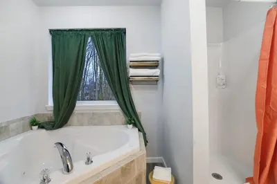 a bathroom with a tub and a green shower curtain at Spacious Vacation Home Tobyhanna Gym BBQ Boat in Pocono Country Place