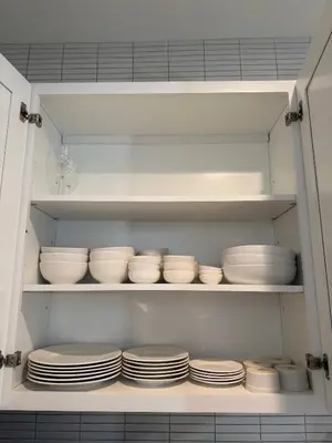 a kitchen cabinet filled with white plates and bowls at Modern 3BR Home | Chic & Cozy | 30 Min NYC Access in Jersey City