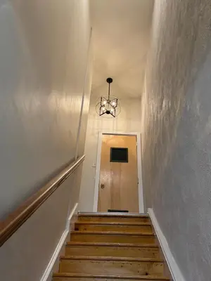 a hallway with a staircase with a chandelier at 3961 Baltimore Penn Campus in Philadelphia