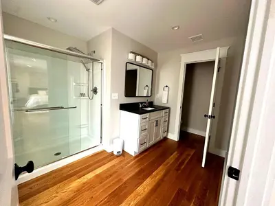 a bathroom with a glass shower and a wooden floor at Luxury 3BR with King Beds in Montgomery Village in Montgomery